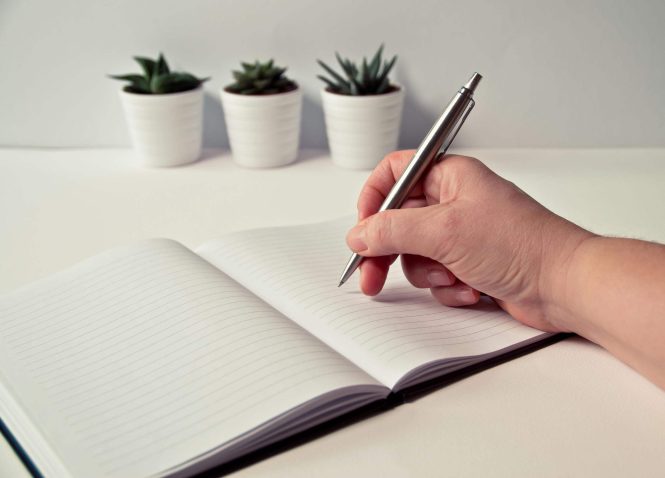 Person writing on a book 